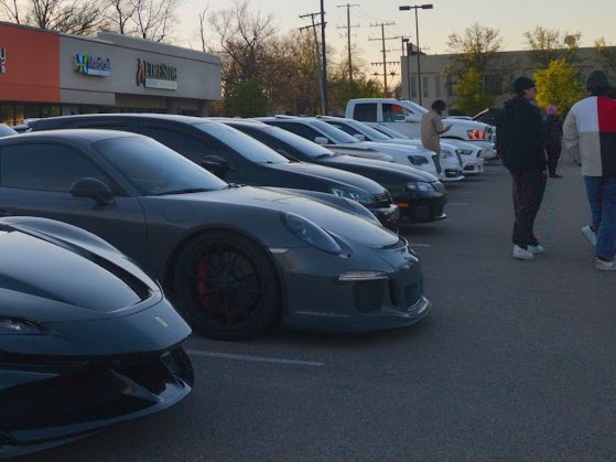 A row of cars, including a grey Porsche 911 GT3, at a car meet.