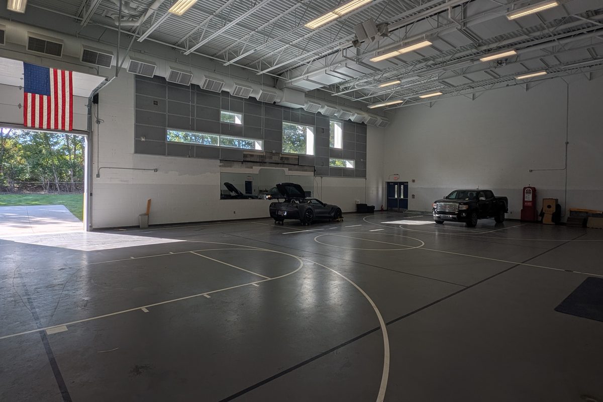 The Paddock: a large heated indoor space with member cars parked inside and its overhead door open.